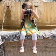 Little girl taking pictures wearing white mary jane shoes