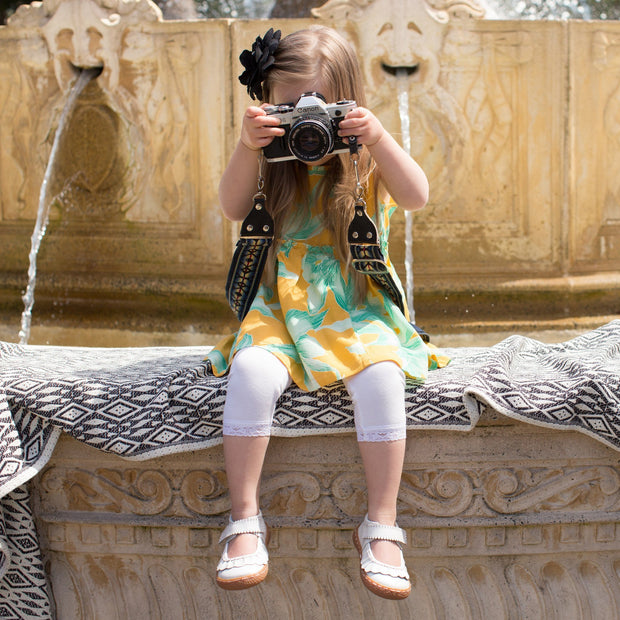 Little girl taking pictures wearing white mary jane shoes